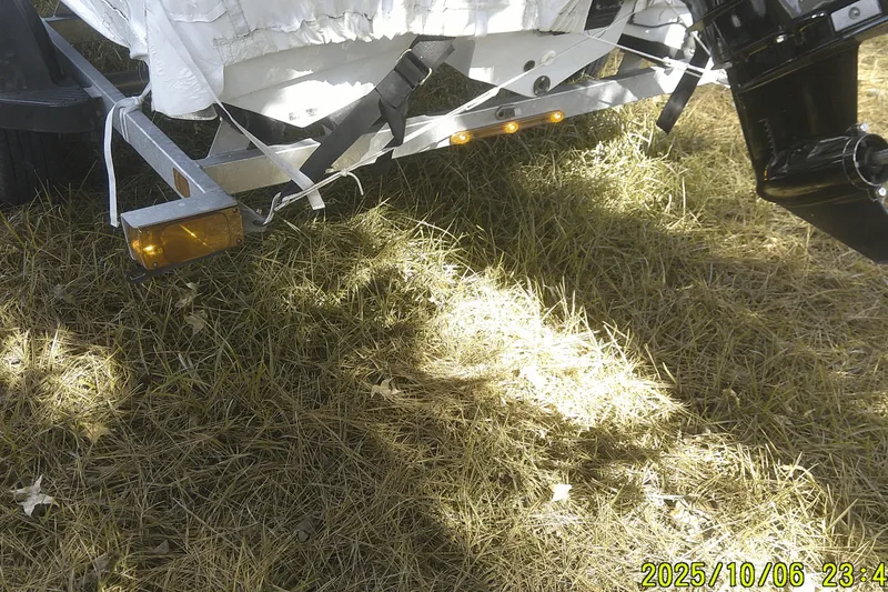 Slide: The Image of 2024 Mako Pro Skiff 15 CC boat trailer on grass, showing rear lights and motor. - 3