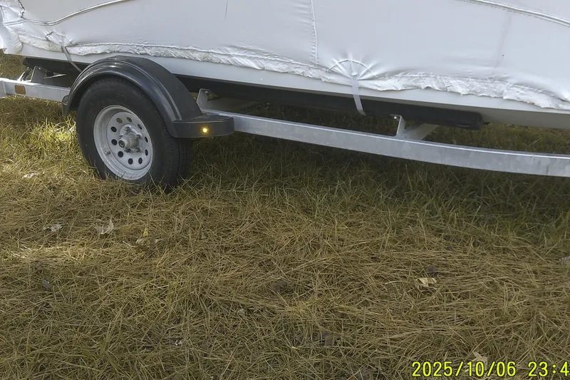 Slide: The Image of Trailer with a covered 2024 Mako Pro Skiff 15 CC boat on grassy ground. - 5