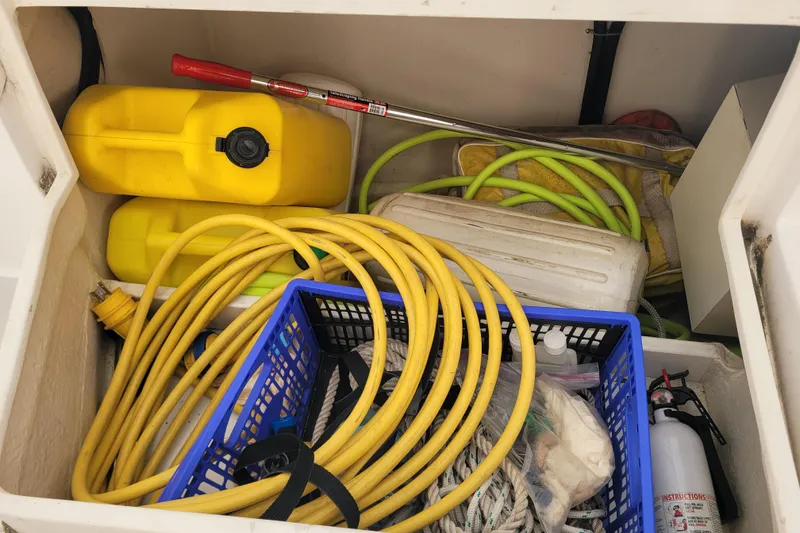 Slide: The Image of Storage compartment of a 2006 Catalina 320 sailboat with hoses, fuel containers, and safety equipment. - 19