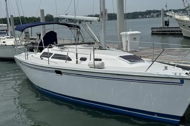 Slide: The Image of 2006 Catalina 320 MkII sailboat docked at marina, featuring sleek white hull and blue accents. - 2