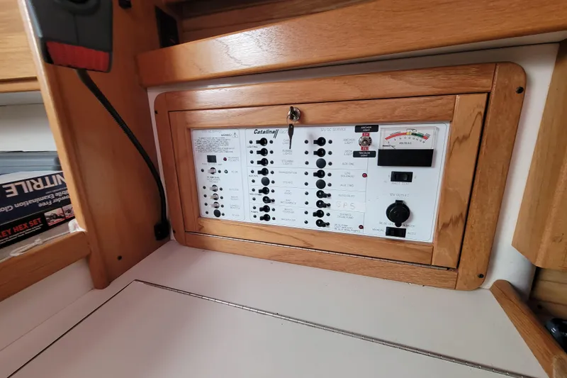 Slide: The Image of Electrical panel of a 2006 Catalina 320 sailboat with wooden frame and control switches. - 23