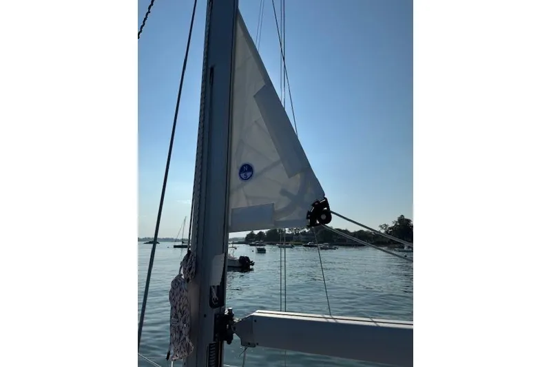 Slide: The Image of Sailboat mast and sail on a 2006 Catalina 320 MkII, with a scenic water backdrop. - 6