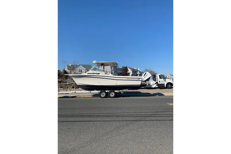 Slide: The Image of 1992 Grady-White Dolphin 251 boat on trailer, parked roadside under clear blue sky. - 1