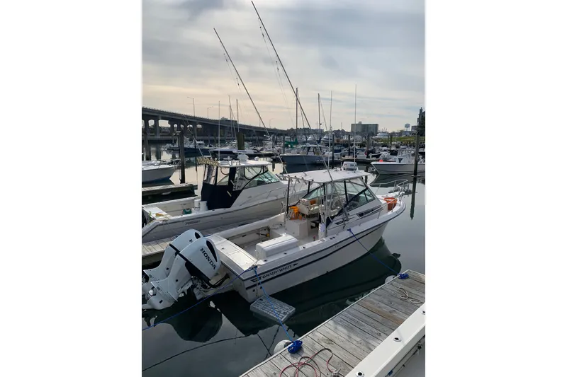 Slide: The Image of 1992 Grady-White Dolphin 251 boat docked in a marina with fishing rods. - 2