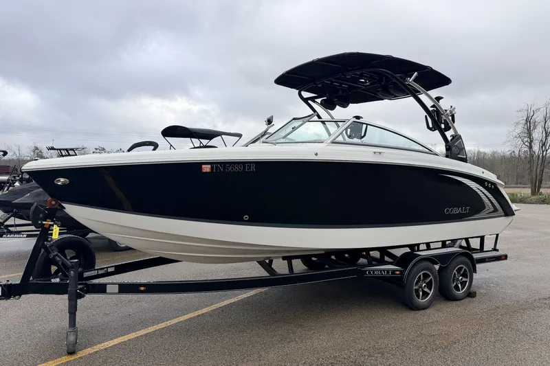 The Image of 2019 Cobalt R5 Surf boat on trailer, black and white design, overcast sky. - 14