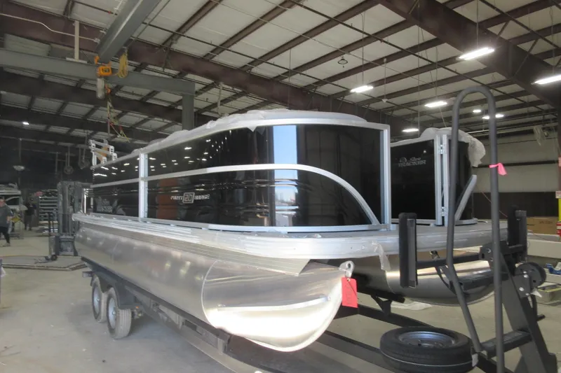 The Image of 2026 Sun Tracker Party Barge 20 DLX pontoon boat in a warehouse setting. - 1