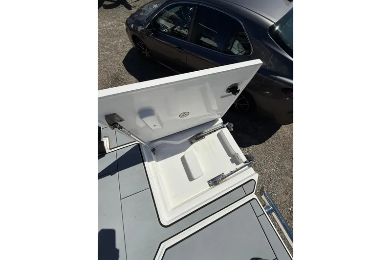 Slide: The Image of Open storage compartment on 2023 Aviara AV32 I/O boat, with car in background. - 9