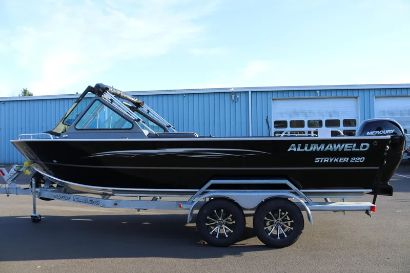The Image of 2026 Alumaweld Stryker 220 boat on trailer, parked outside a blue building. - 1