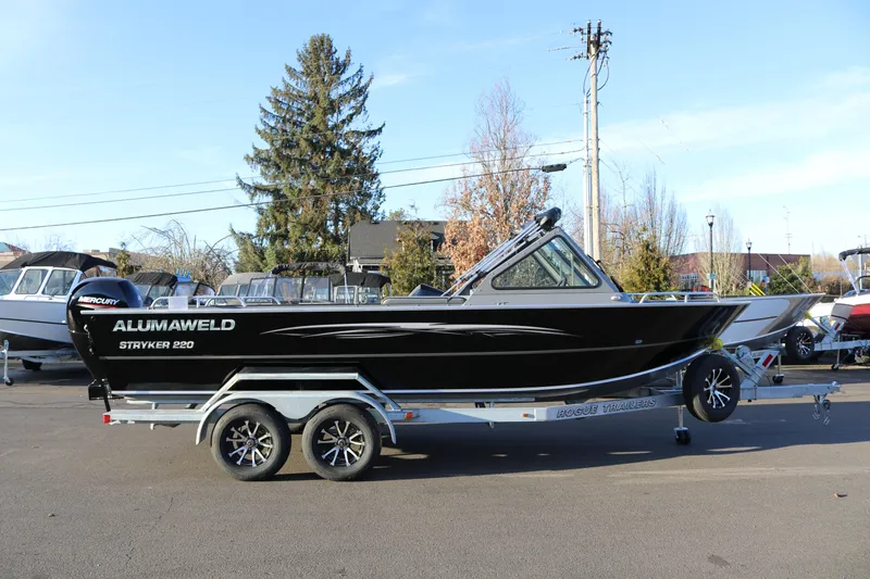 Slide: The Image of 2026 Alumaweld Stryker 220 boat on trailer, parked outdoors, side view. - 4