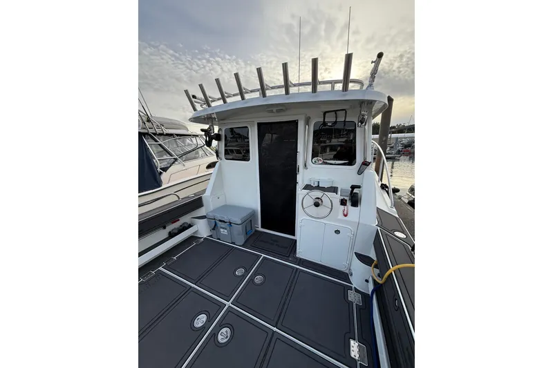 Slide: The Image of 2005 Ocean Sport Roamer #12 boat docked, featuring spacious deck and fishing rod holders. - 13