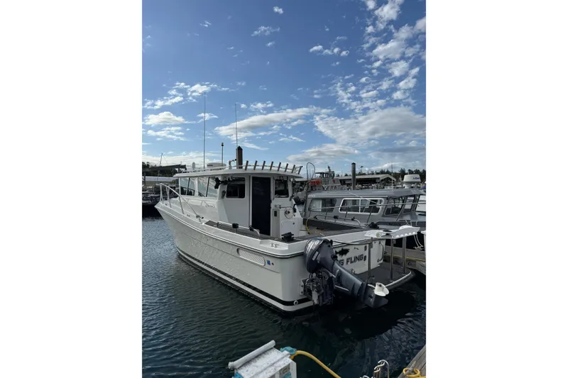 Slide: The Image of 2005 Ocean Sport Roamer #12 boat docked under a partly cloudy sky. - 17