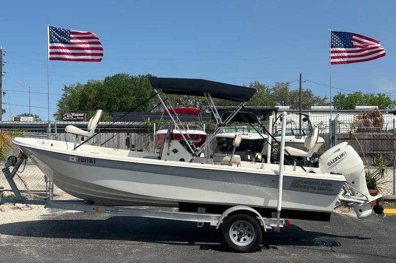 The Image of 2020 Carolina Skiff 192 JLS boat on trailer, with American flags in the background. - 1