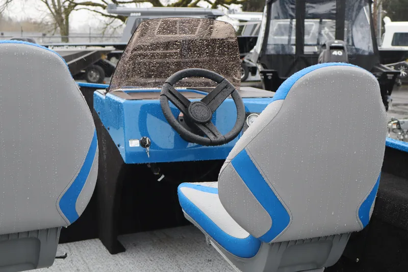 Slide: The Image of 2026 Smoker Craft Lazer 161 boat interior with blue and gray seats, steering wheel, and dashboard. - 8