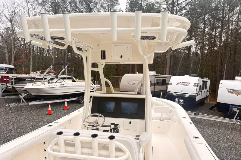 Slide: The Image of 2023 Sea Born LX26 Center Console boat in a storage lot with trailers and trees. - 6