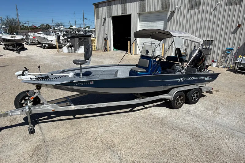 The Image of 2015 Xpress H22B Bay boat on trailer, parked outside a warehouse. - 1