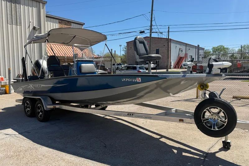 Slide: The Image of 2015 Xpress H22B Bay boat on trailer, parked outdoors near industrial buildings. - 6