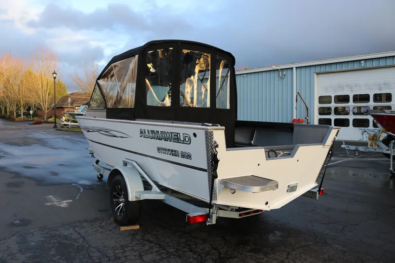 Slide: The Image of 2026 Alumaweld Stryker 202 boat with canopy, parked outdoors near a blue building. - 4