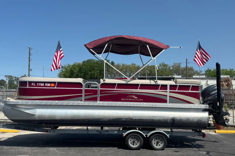 The Image of 2010 Bennington 2274GLi pontoon boat on trailer with American flags, Yamaha motor, and canopy. - 0