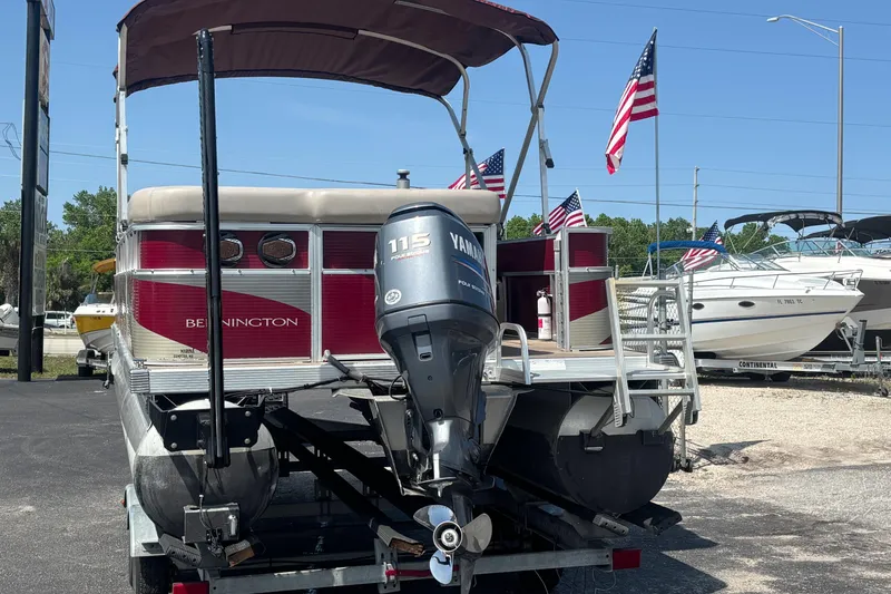 Slide: The Image of 2010 Bennington 2274GLi pontoon boat with Yamaha 115 engine, displayed outdoors with American flags. - 2