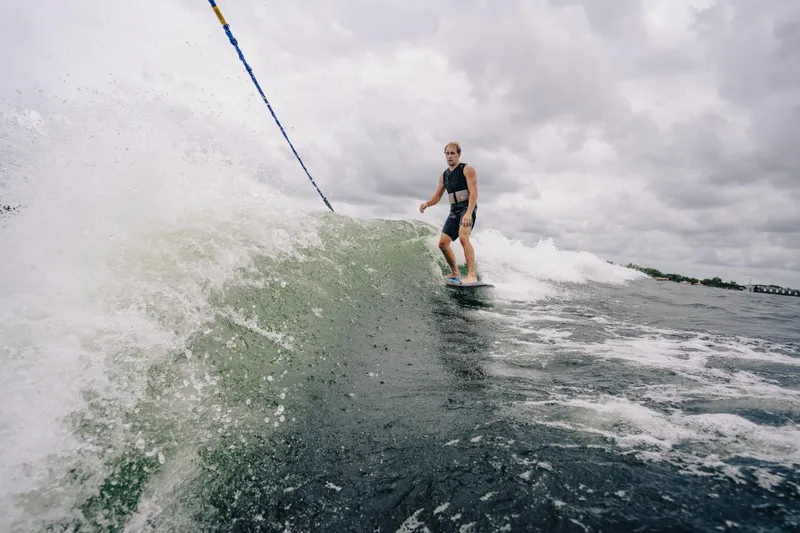 Slide: The Image of Surfer riding wave behind 2024 Montara 23 Surf Boss 2.0 CW boat. - 2