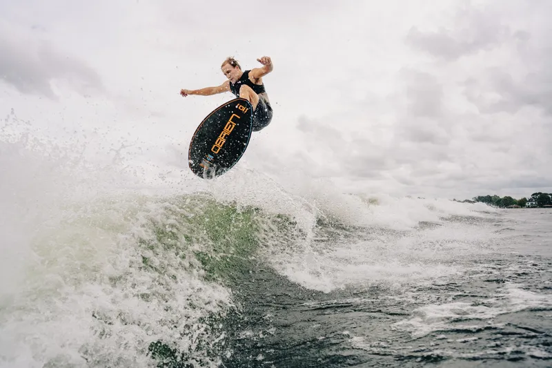 Slide: The Image of Surfer catching air on waves behind 2024 Montara 23 Surf Boss 2.0 CW boat. - 3