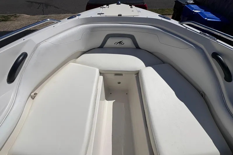 Slide: The Image of 2009 Monterey 214FS boat interior with white cushioned seating and storage area. - 18