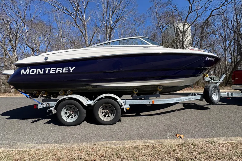 Slide: The Image of 2009 Monterey 214FS boat on trailer, parked on a road with trees in background. - 5