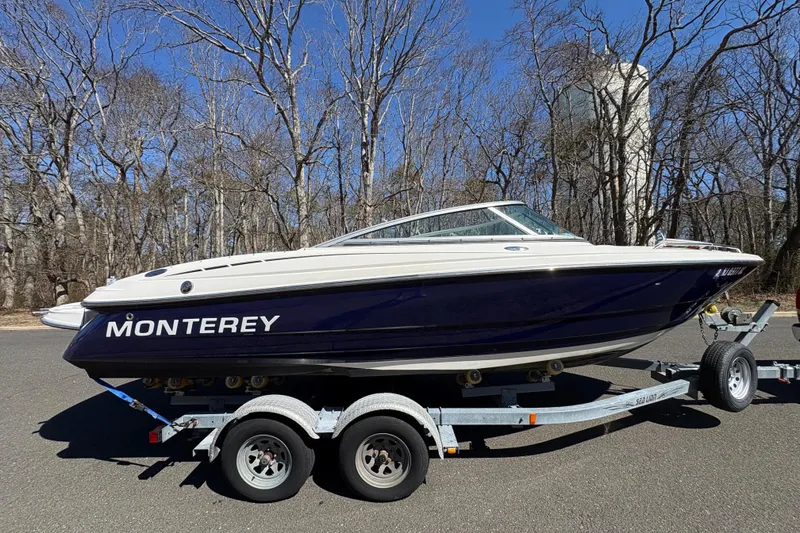 Slide: The Image of 2009 Monterey 214FS boat on trailer, parked on road with trees in background. - 7