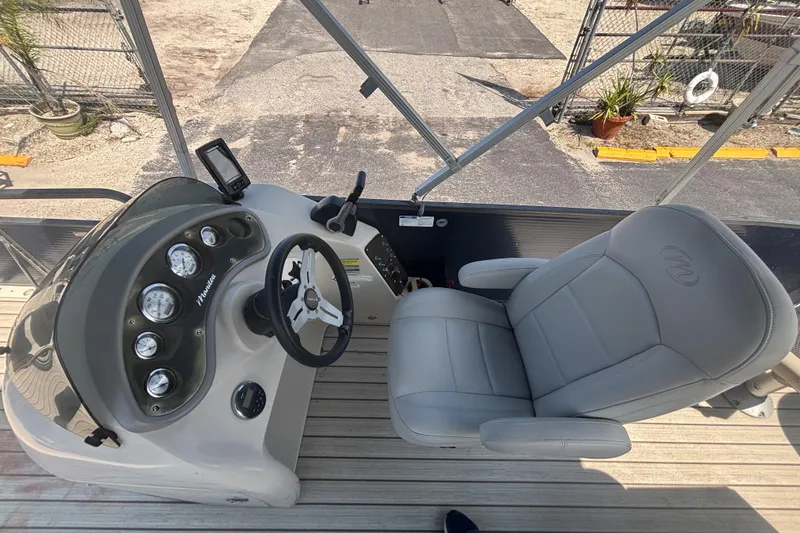 Slide: The Image of 2015 Manitou 20 Oasis Angler boat interior with steering console and captain's chair. - 13