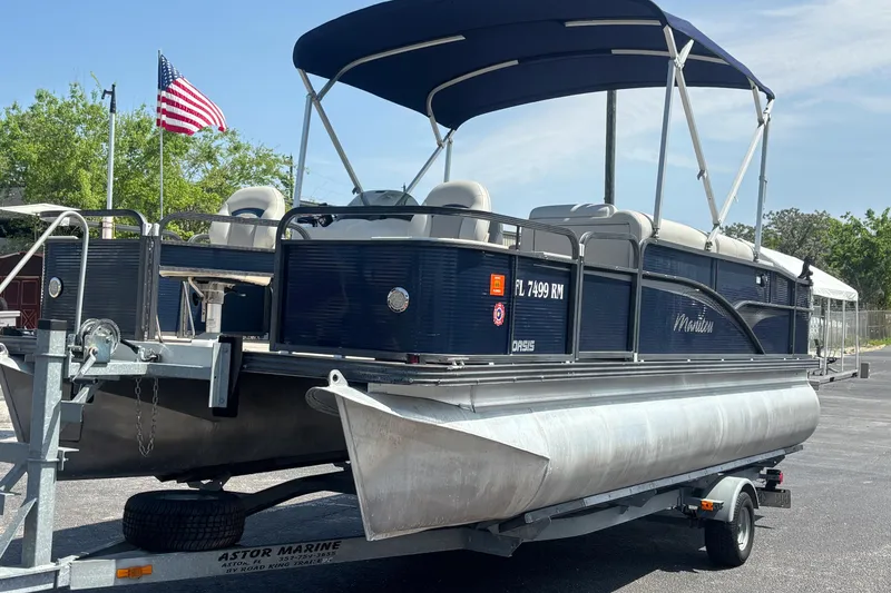 Slide: The Image of 2015 Manitou 20 Oasis Angler pontoon boat on trailer with American flag in background. - 9