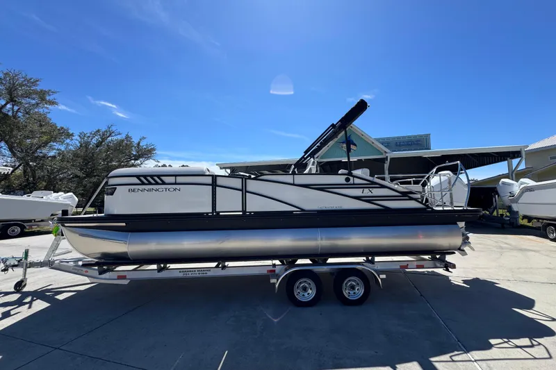The Image of 2026 Bennington 22 LXS Swingback pontoon boat on trailer under clear blue sky. - 1
