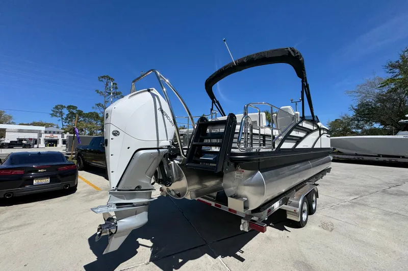 Slide: The Image of 2026 Bennington 22 LXS Swingback pontoon boat on trailer, featuring a powerful Mercury outboard motor. - 11