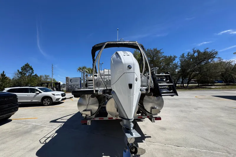 Slide: The Image of 2026 Bennington 22 LXS Swingback pontoon boat with powerful outboard motor in a parking lot. - 13