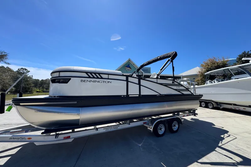 Slide: The Image of 2026 Bennington 22 LXS Swingback pontoon boat on trailer under clear blue sky. - 2