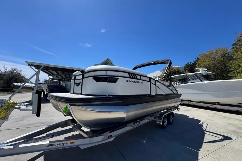 Slide: The Image of 2026 Bennington 22 LXS Swingback pontoon boat on trailer under clear blue sky. - 3