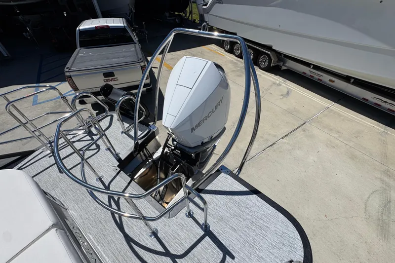 Slide: The Image of 2026 Bennington 22 LXS Swingback with Mercury outboard engine, parked near a GMC truck. - 35