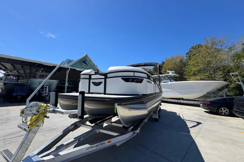 Slide: The Image of 2026 Bennington 22 LXS Swingback pontoon boat on trailer under clear blue sky. - 4