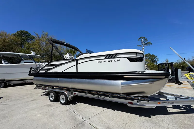 Slide: The Image of 2026 Bennington 22 LXS Swingback pontoon boat on trailer under clear blue sky. - 7