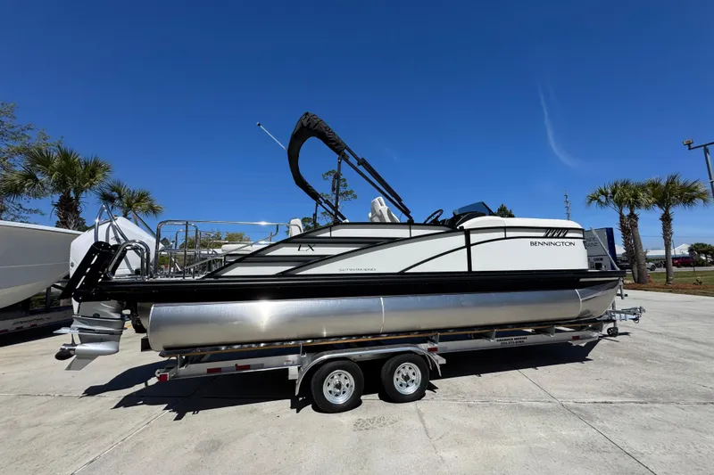 Slide: The Image of 2026 Bennington 22 LXS Swingback pontoon boat on trailer under clear blue sky. - 9
