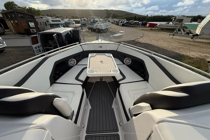 Slide: The Image of 2019 Monterey 328SS Super Sport boat interior with seating and table, parked in a marina. - 21