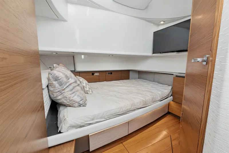 Slide: The Image of 2022 Tiara 38LS yacht cabin with bed, wooden accents, and mounted TV. - 15