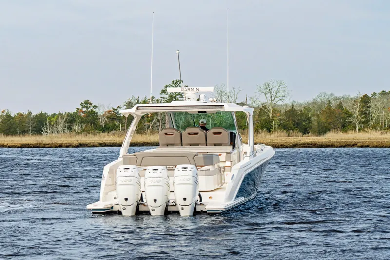 Slide: The Image of 2022 Tiara 38LS boat with triple outboard engines on a scenic waterway. - 2