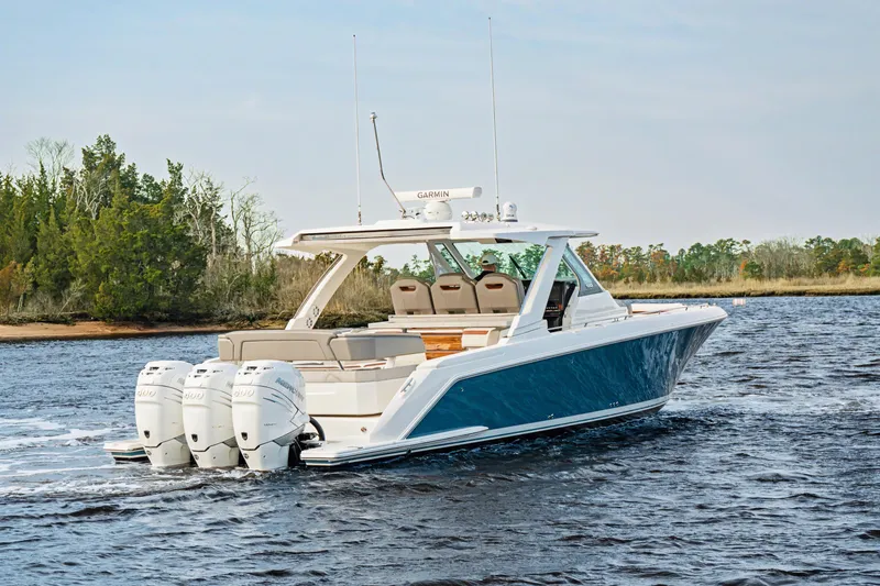 Slide: The Image of 2022 Tiara 38LS boat cruising on a calm river with lush greenery. - 3