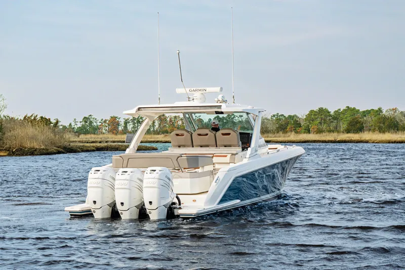 Slide: The Image of 2022 Tiara 38LS boat cruising on a scenic waterway with four outboard engines. - 4