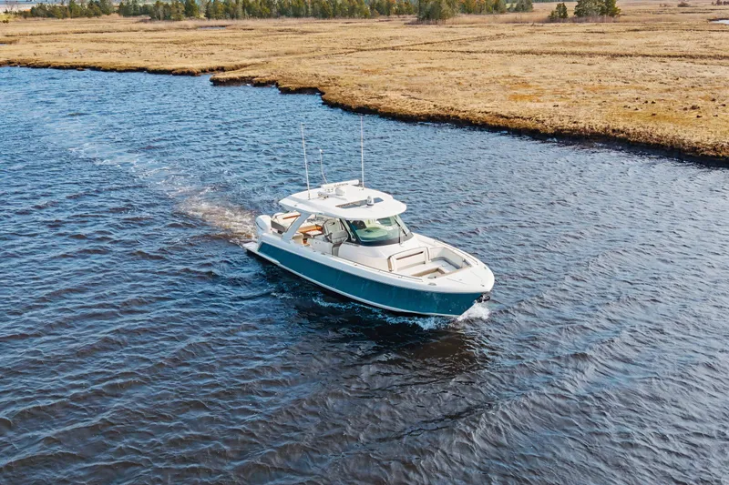 Slide: The Image of 2022 Tiara 38LS boat cruising on a serene river with grassy banks. - 7