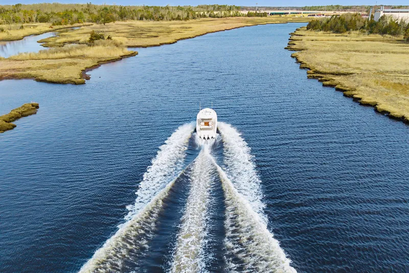 Slide: The Image of Tiara 38LS 2022 boat cruising on a scenic river with lush banks. - 8