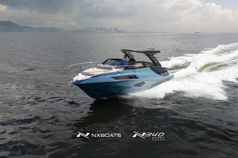 Slide: The Image of 2026 NX Boats NX340 cruising on open water with city skyline in background. - 5
