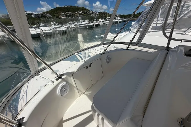Slide: The Image of 2005 Riviera 37 Flybridge interior with marina view, featuring white seating and clear windows. - 20