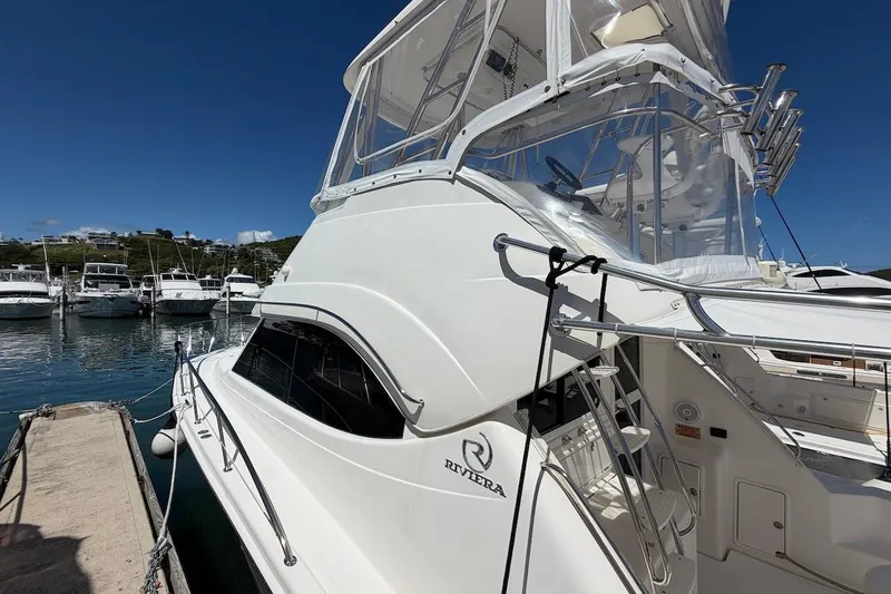 Slide: The Image of 2005 Riviera 37 Flybridge yacht docked at marina under clear blue sky. - 28