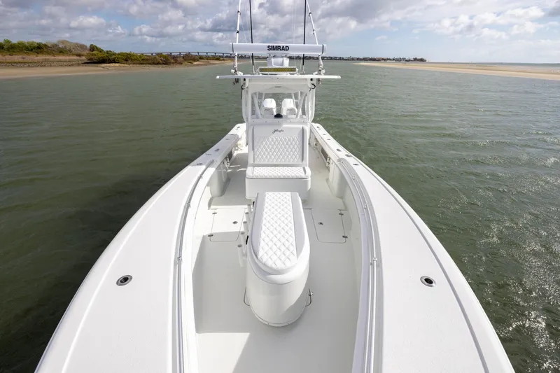 Slide: The Image of 2014 Yellowfin 32 Offshore boat on calm water, featuring spacious deck and seating. - 12